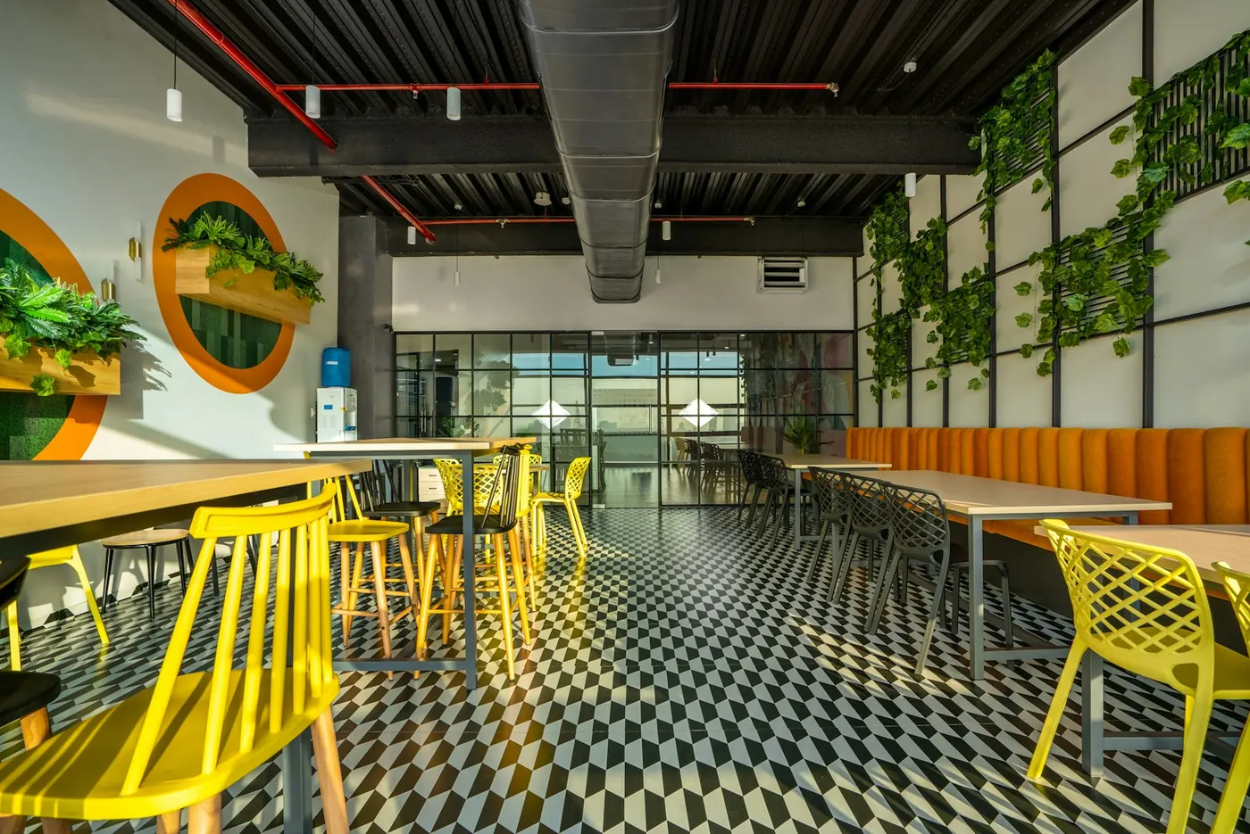 A modern dining room with yellow chairs, checkered flooring and wall greenery